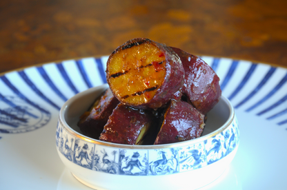 Close-up of charred white sweet potato rounds glazed with tamarind, gourmet BBQ side dish delivery Algarve