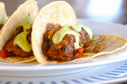 Close-up of a Mexican-style beef taco, adobo-marinated and grilled, with avocado crema